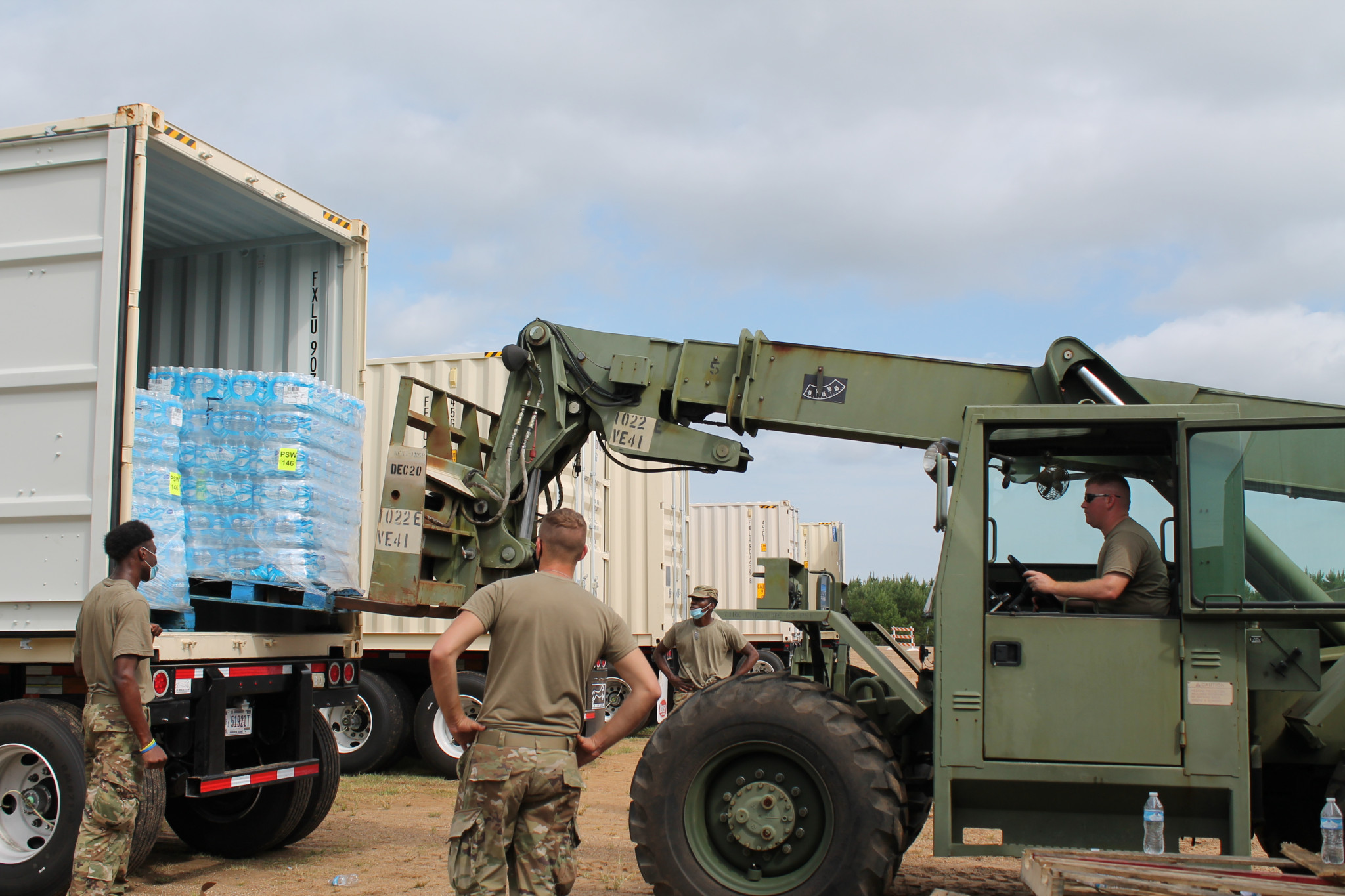 National Guardsmen use military equipment at the North Louisiana Exhibition Center Sunday to remove pallets of water brought in for parish residents